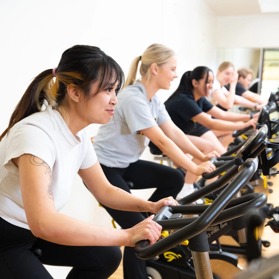 Students pedal on stationary bikes as part a spin class